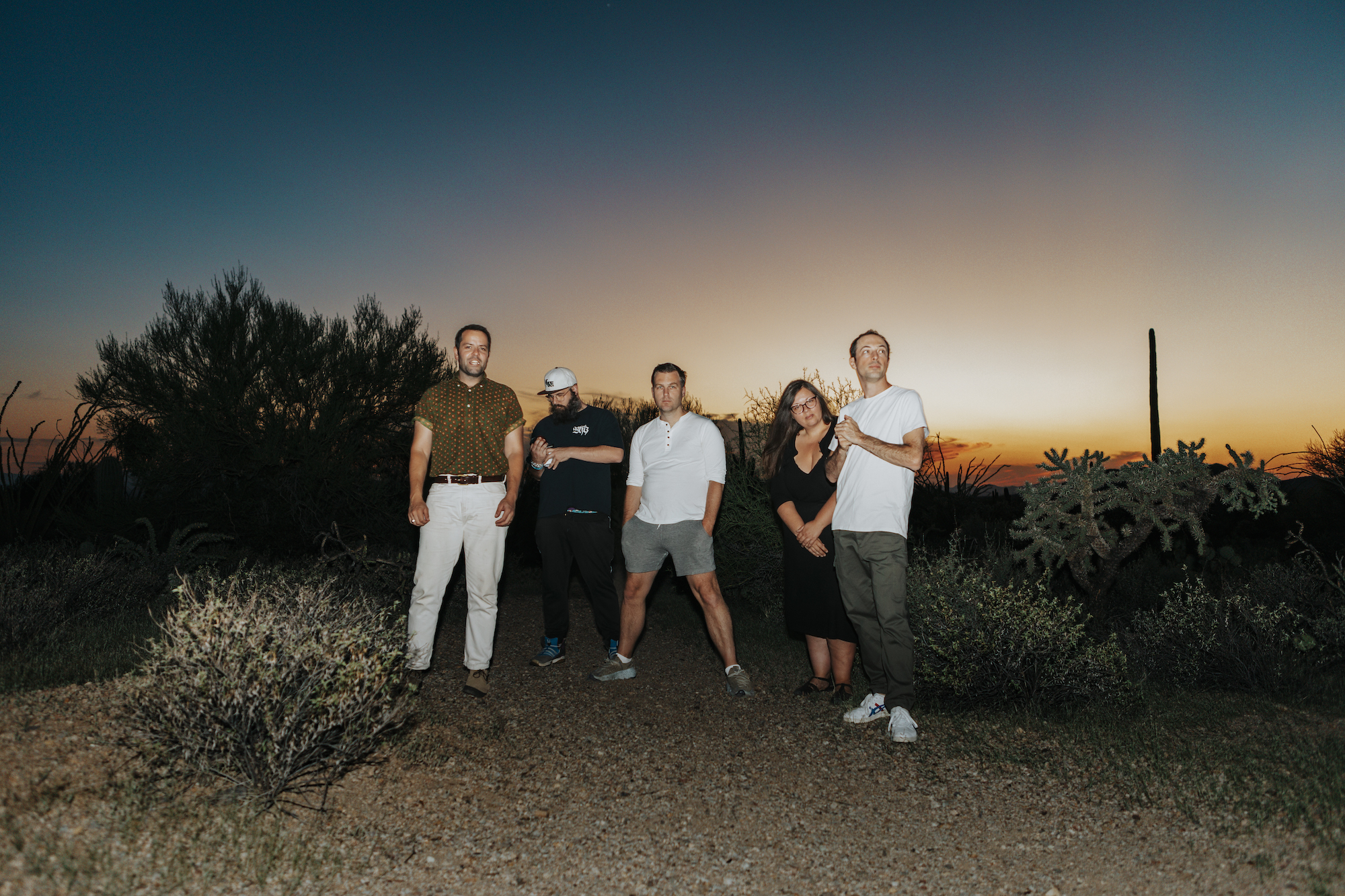 Fucked Up photographed in the desert twilight. From left to right: Jonah Falco, Damian Abraham, Mike Haliechuk, Sandy Miranda, and Josh Zucker.